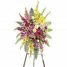Standing floral arrangement with lilies, gladiolus, roses, and ferns on a wooden easel.