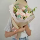 Woman holding a bouquet of pink roses and white flowers.