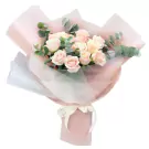 Bouquet of pink and cream roses with eucalyptus leaves in pink and white paper wrap.