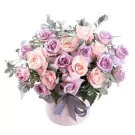 Pink and purple roses in a light pink hatbox with a gray ribbon.