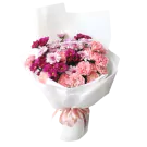 Bouquet of pink and magenta carnations and chrysanthemums in white paper, tied with a pink ribbon.