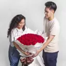 Couple holding a giant bouquet of 200 red roses.
