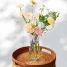 Vase of light pink and yellow spring flowers with a pink ribbon.