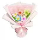 Bouquet of artificial plumeria flowers in various colors, wrapped in white and pink paper with a pink ribbon.