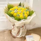 Yellow ping pong chrysanthemums with baby's breath and greenery in a cream and clear wrapper tied with ribbon.