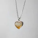 Silver chain necklace with a heart-shaped, raw yellow crystal pendant.