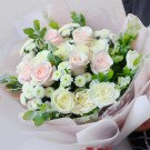 Bouquet of pink and white roses, carnations, and small white flowers in pink paper.