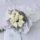White carnation bouquet wrapped in white paper, with purple accent flowers.