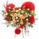 Floral arrangement with peach roses, white flowers, and red accents on a wooden stand.