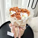 Peach roses and white orchids in a bouquet, wrapped in sheer fabric and paper, with a "Happy Day" card.