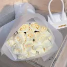 White roses bouquet with a mini white Jacquemus bag.