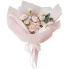 Pastel bouquet of roses, hydrangeas, and carnations with pink paper and ribbon.