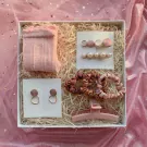 Pink gift box with socks, earrings, hair clips, scrunchies, and a claw clip.