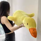 Giant yellow duck plush toy held by a woman wearing a black tank top and skirt.