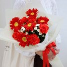 Bouquet of red gerbera daisies and roses with white calimero chrysanthemums, tied with a red ribbon.