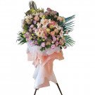 A grand floral arrangement on a stand, featuring orchids, carnations, and other blooms in pink, purple, and white.