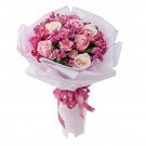 Bouquet of pink and cream roses with carnations, wrapped in white paper and tied with a pink ribbon.