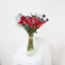 A bouquet of red roses and silver flowers in a glass vase.