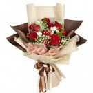 Bouquet of red roses, white flowers, and greenery, wrapped in paper and tied with a ribbon.