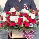 Christmas flower box with red and white roses, carnations, pine cones, and gold ornaments.