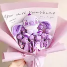 Purple Stitch plush toy surrounded by purple-wrapped candies in a bouquet.