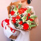 Vibrant bouquet of red roses, snapdragons, and baby's breath with a red ribbon.