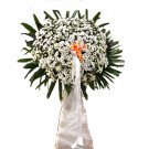 Standing funeral flower arrangement with white chrysanthemums and green leaves.