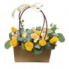 Yellow and pink roses and carnations in a brown basket with a ribbon bow.