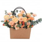 A flower basket with peach roses, gerbera daisies, and carnations in a brown paper bag with handles.