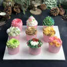 Nine colorful cupcakes with swirled frosting arranged on a white platter.