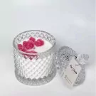 Scented candle in a clear glass jar with pink rose wax decorations and a detached lid.