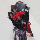 Bouquet of red roses in black wrapping with red ribbon.