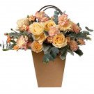 Floral arrangement in a brown paper bag with yellow roses, pink carnations, and eucalyptus.