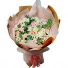 A bouquet of pink and white roses with greenery, wrapped in brown and pink paper and tied with a pink ribbon.