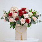 Box of red and cream roses with delicate white filler flowers and greenery.