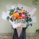 Bouquet of orange and pink chrysanthemums with baby's breath and eucalyptus.