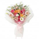 Bouquet of pink and orange roses, gerberas, lisianthus, and carnations wrapped in white paper and tied with a pink ribbon.