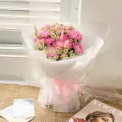 Pink carnation and daisy bouquet with fluffy pink accents, wrapped in white paper and tied with a pink ribbon.