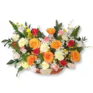 Basket arrangement of orange, red, and pink roses with white carnations and greenery.