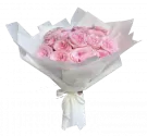 Pink roses in white paper bouquet with a white ribbon.