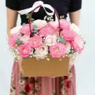 Basket of pink and cream roses with baby's breath, tied with a white ribbon.