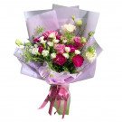 Bouquet of pink roses, white carnations, and white eustoma, wrapped in light purple paper and tied with a pink ribbon.