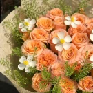 A bouquet of peach roses with delicate white flowers and greenery.