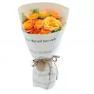 Bouquet of orange roses wrapped in sheet music paper, tied with burlap and ribbon.