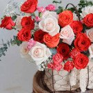 Basket of red and white roses with carnations in a wire basket.