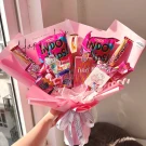 Pink candy bouquet with Hello Kitty and assorted snacks, wrapped in pink paper and tied with a Chanel ribbon.