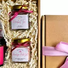 Gift set with two glass jars of tea and pink salt, a cardboard box, and pink ribbon.