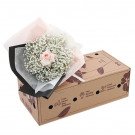 Pink rose and baby's breath bouquet in floral packaging on a brown box.