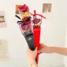 Two gold-dipped roses in red and black wrappers held by hands.