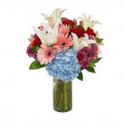 Vase of colorful flowers including roses, lilies, hydrangeas, and gerberas.